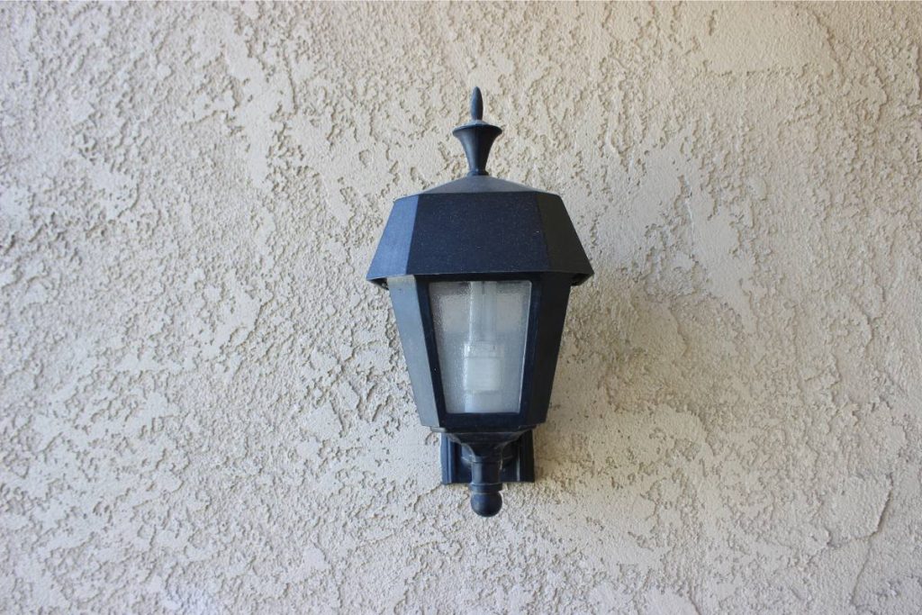 black lamp hangs on stucco wall